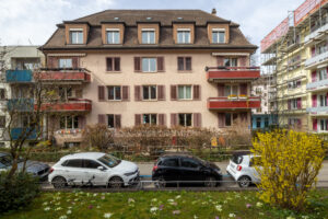 Riedmattstrasse 8 strassenseitig frontal fotografiert. Sträucher und Wiese im unteren Bildrand.